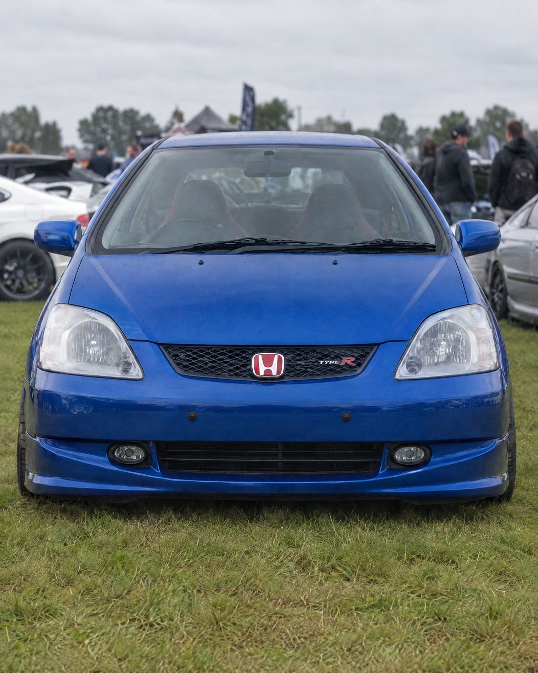 Blue hot hatch on show grass, plate off, two small pegs on the bumper
