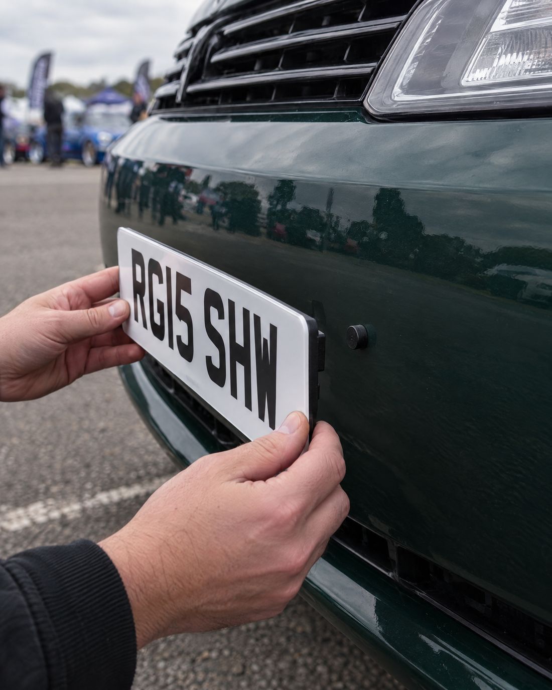 Hands hooking the front plate back onto the bumper pegs