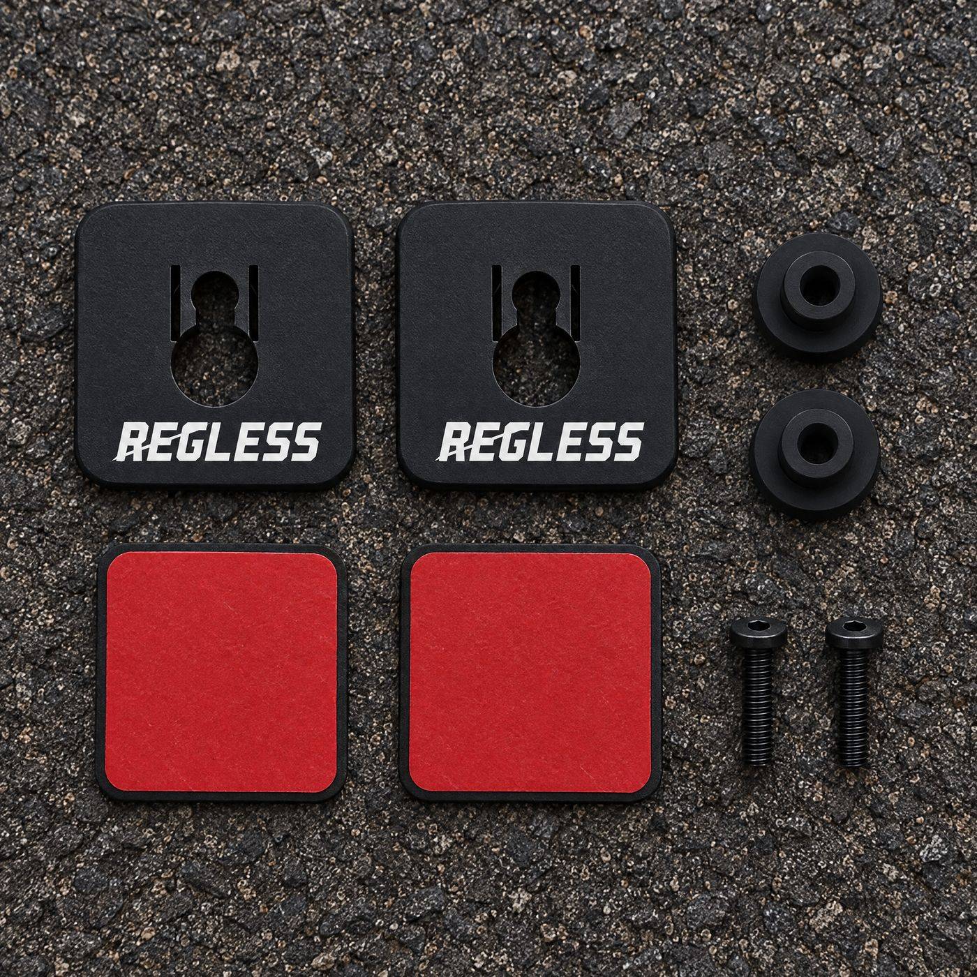 Kit laid out on tarmac: two Regless squares, two round pegs, two red-liner 3M pads and two M4 screws