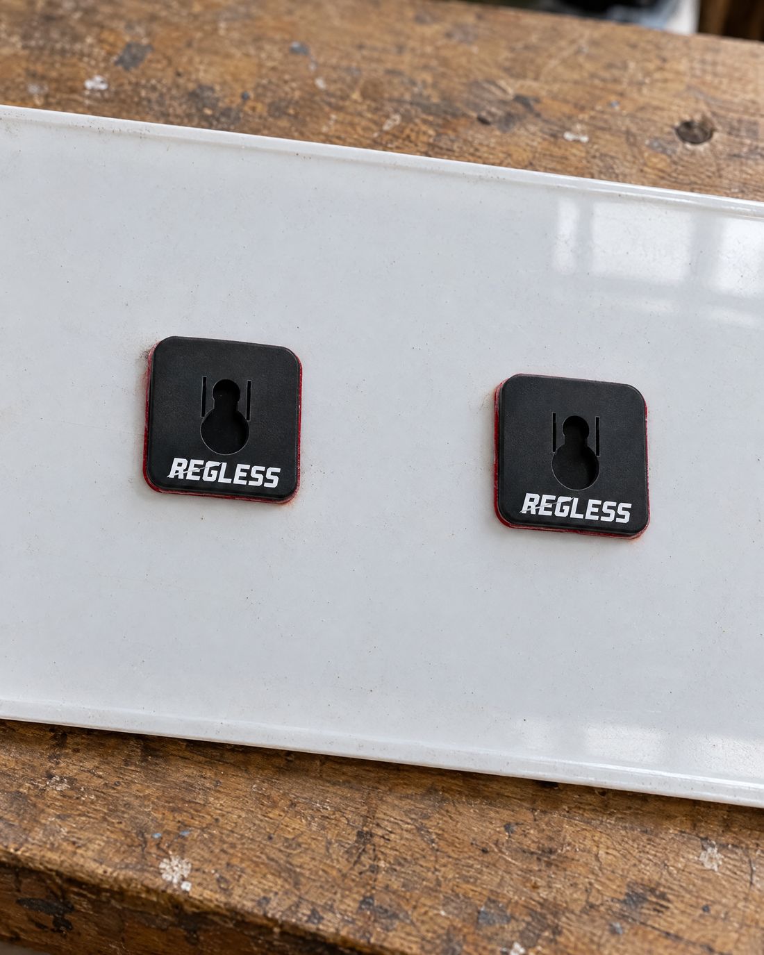 Back of a number plate with two Regless squares stuck on