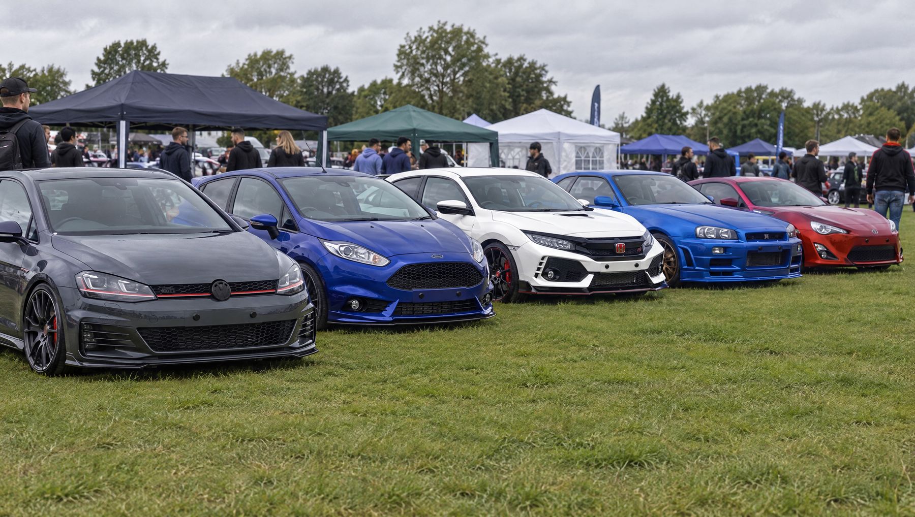 Line-up of modified cars at a show, all running plate-free